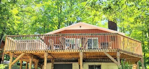 Une cabane en bois dotée d’un balcon, entourée d’arbres.