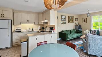 A modern kitchen with a dining area, a green sofa, and a patterned armchair.