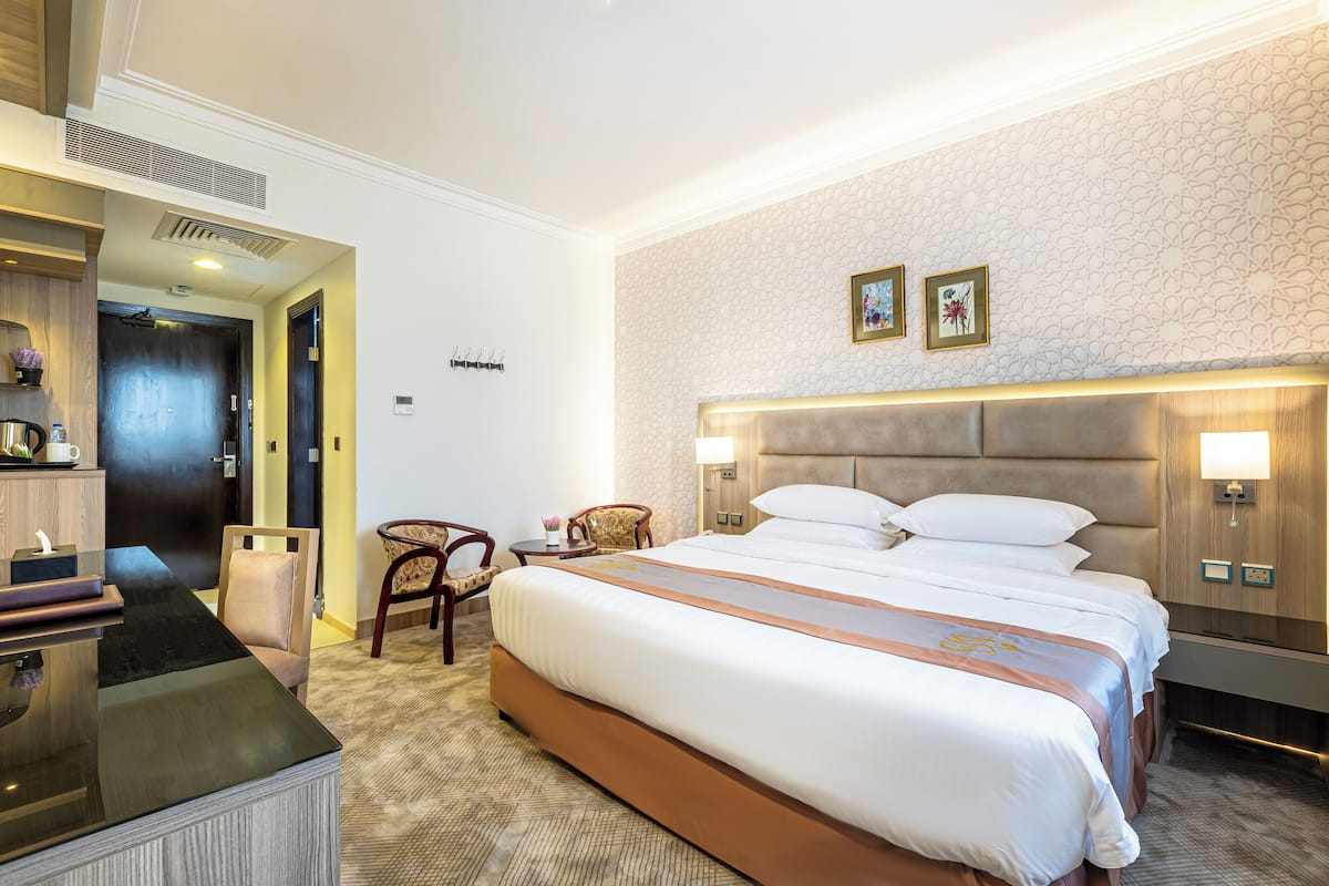 Una habitación de hotel con una cama grande, mesitas de noche, un escritorio y una silla.