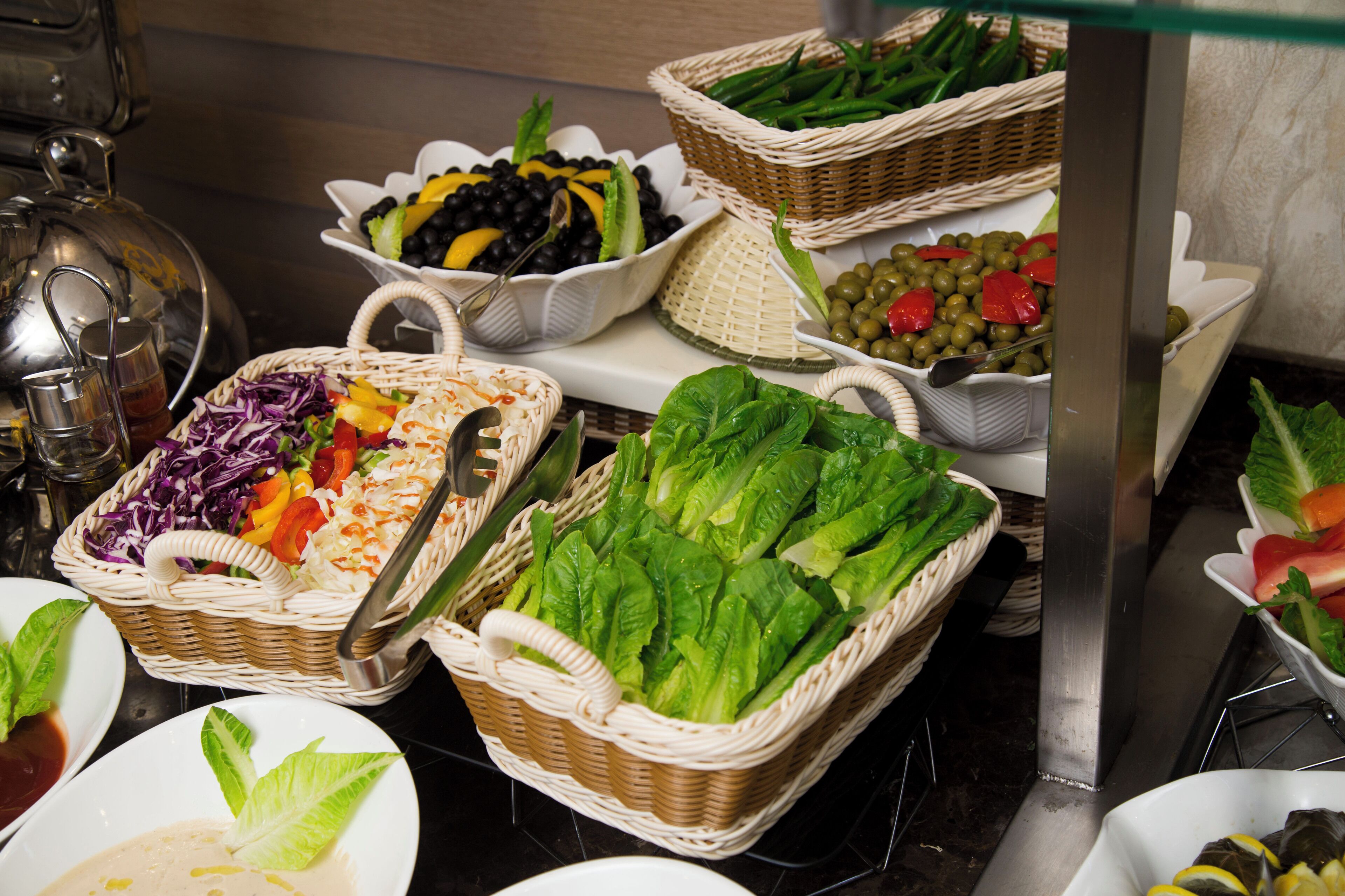 Een buffet met diverse gerechten, waaronder salades, fruit en groenten.