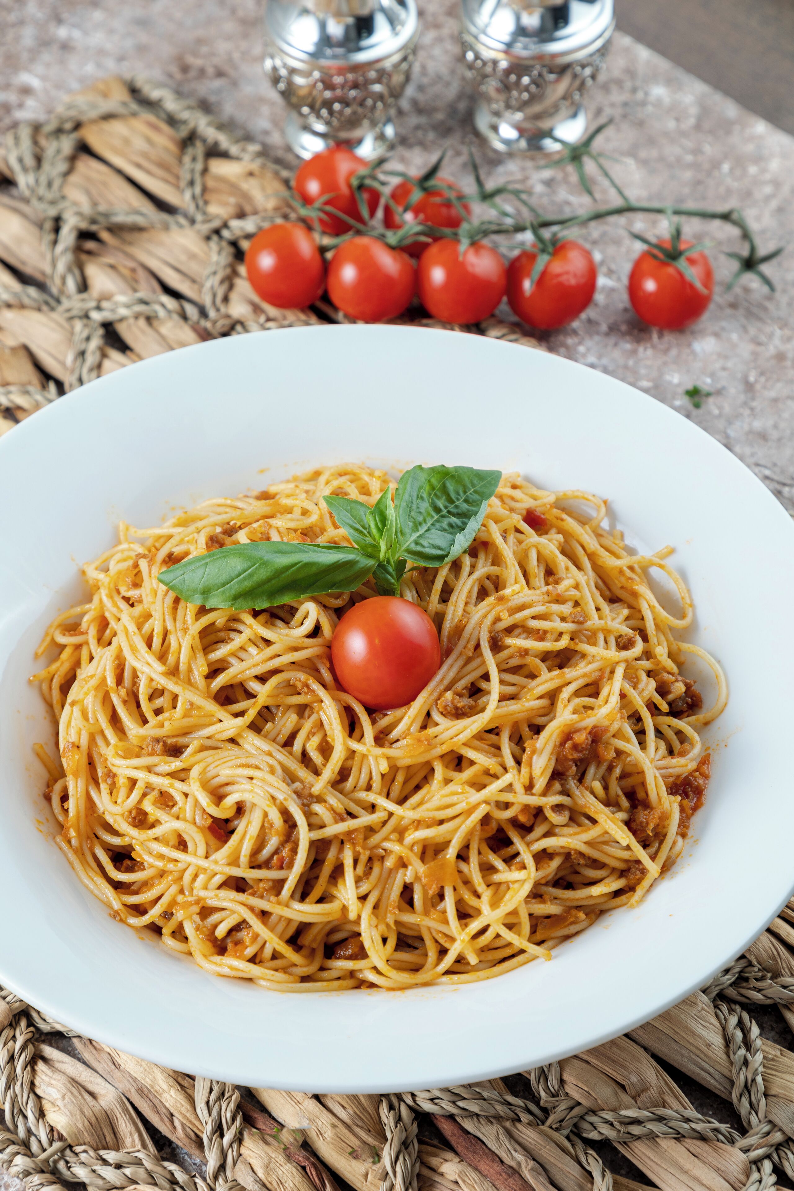 Une assiette de spaghettis à la sauce tomate, garnie d’une feuille de basilic.