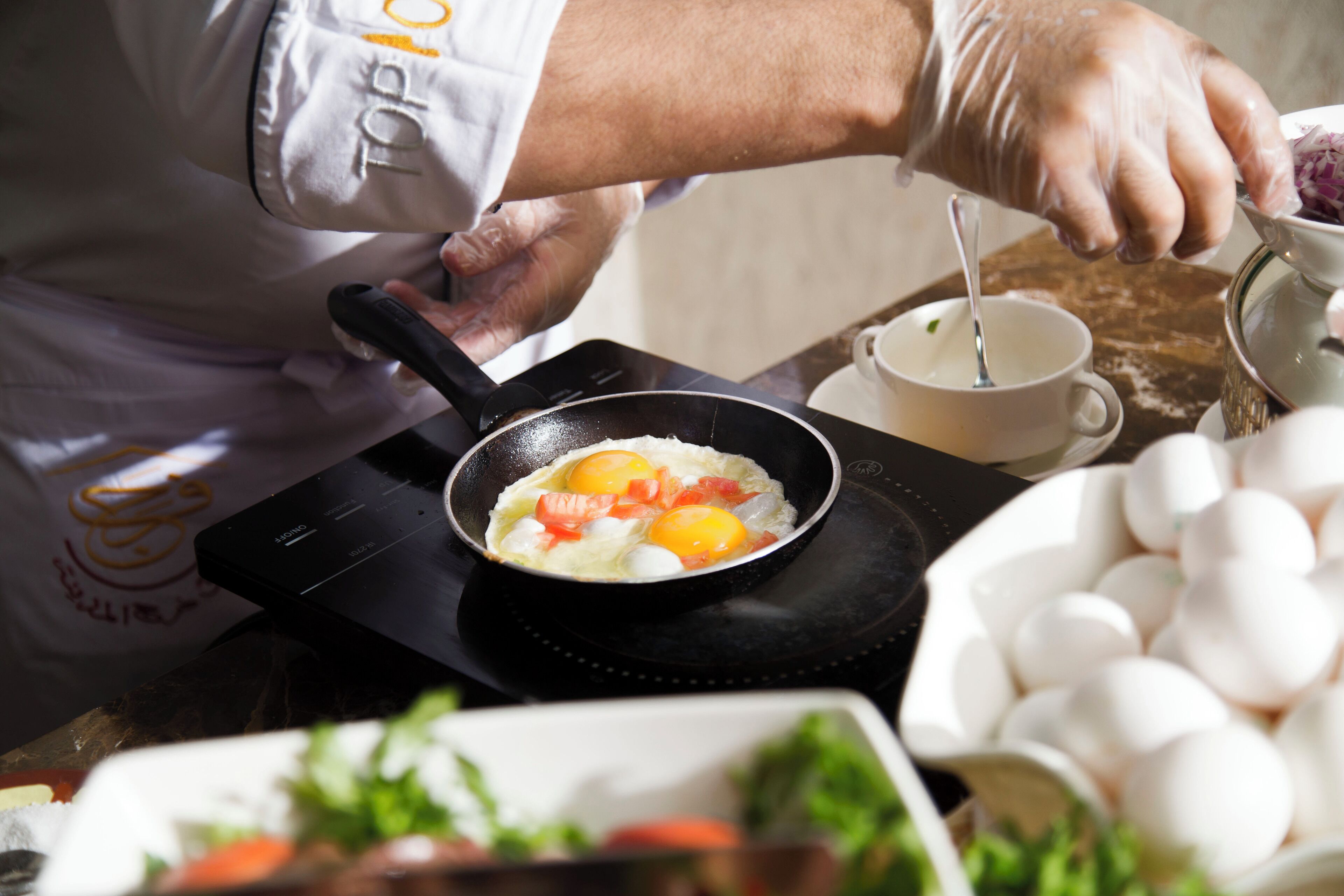 Una persona cocinando huevos en una sartén sobre una estufa.