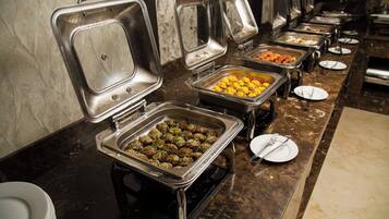 Montaje de bufé con múltiples estaciones de comida, cada una con una bandeja metálica y un plato.