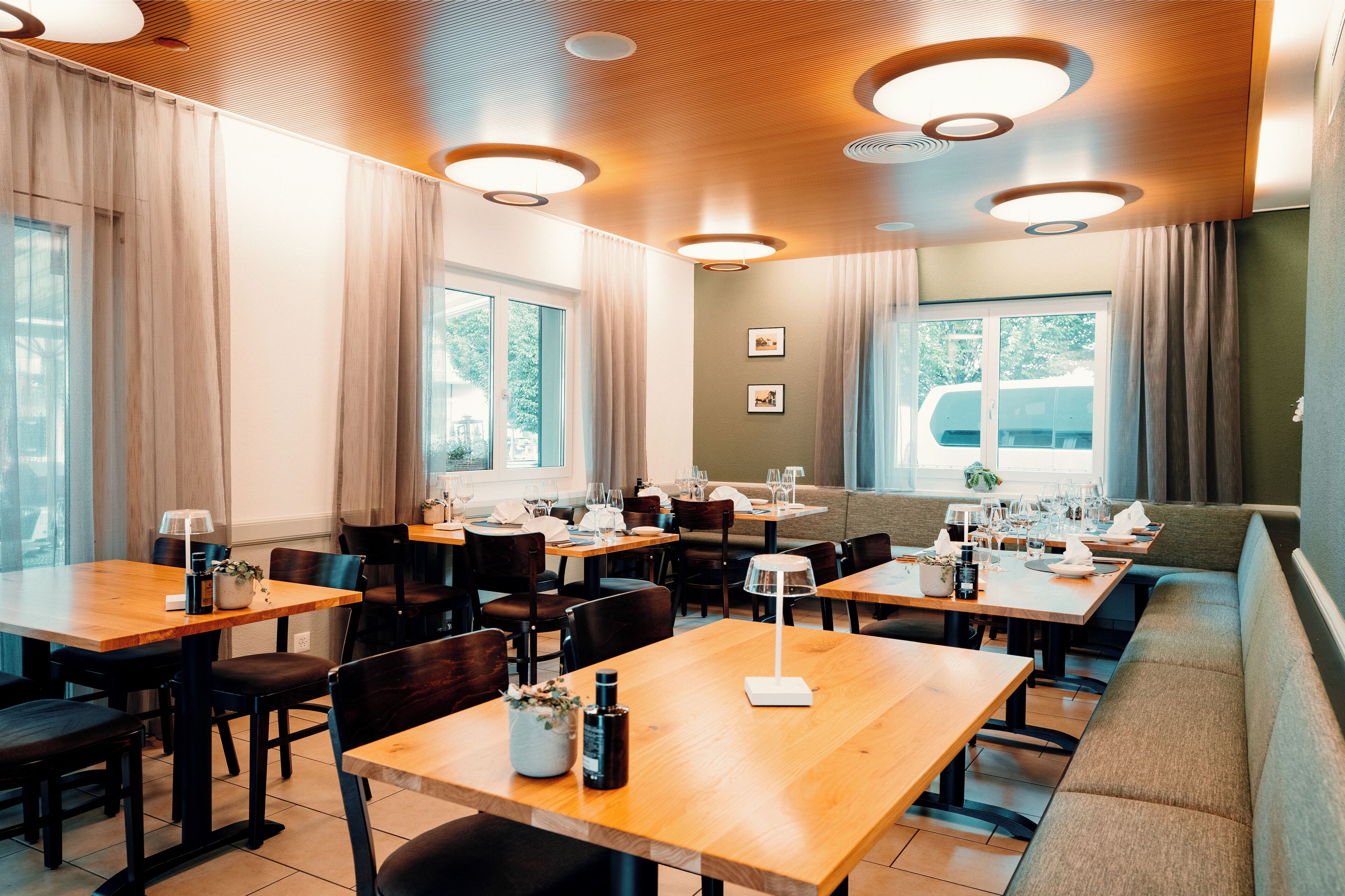 Un restaurante con varias mesas y cabinas, ventanas amplias e iluminación de techo.