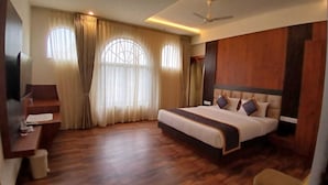 Une chambre d’hôtel spacieuse, dotée d’un grand lit, d’un parquet et d’un bureau avec une chaise.