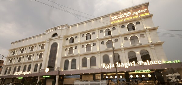 A multi-story building with signage for "Raja Bagiri Palace" and "Pure Veg" restaurant. - PPH Living Rajathagiri Palace Premium (Bengaluru)