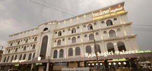 Un edificio de varios pisos con señalización para el Palacio Raja Bagiri y el restaurante Pure Veg.