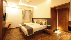 Une chambre d’hôtel avec deux lits, un plancher en bois, un ventilateur de plafond, un appareil de climatisation, une télévision et une armoire.