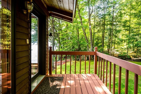 A wooden deck with a railing overlooking a forested area.