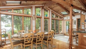 Un comedor espacioso con ventanas amplias, vigas de madera y una lámpara central.