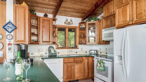 A kitchen with wooden cabinets, a white refrigerator, and a green countertop. - Winnipesaukee Waterfront Home For 12 Sand Beach and Dock For Two 24 Ft Boats (Moultonborough)