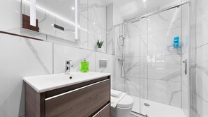 Et moderne badeværelse med et marmorbadevægsbord, en glasbrusekabine og et toilet.