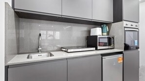 A modern kitchen with a stainless steel sink, a microwave, and a built-in oven. - Cosy Golders Green Studio With Modern Amenities (London)