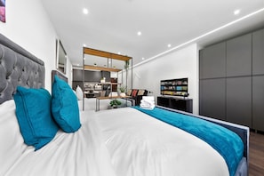 A modern hotel room with a large bed, a desk, and a TV.