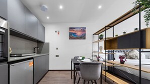 A compact living space with a kitchenette, dining area, and a bed with a headboard. - Chic Studio in Golders Green Near Tube Station (London)