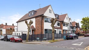 A two-story residential building with a white facade and brown roof tiles. - Stylish Studio in Golders Green Central Location (London)