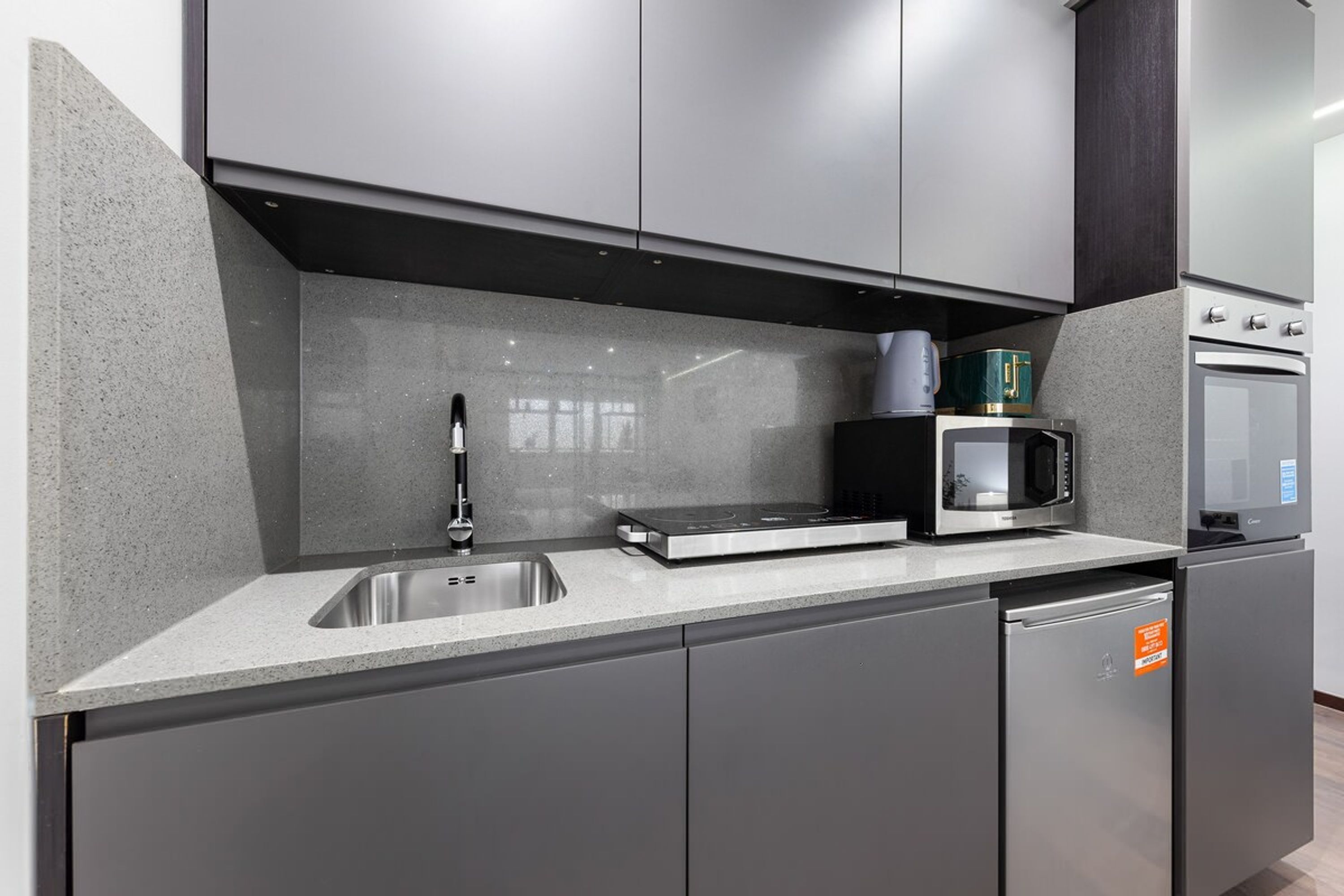Una cocina moderna con un lavamanos de acero inoxidable, un microondas y un horno empotrado.