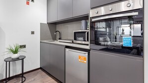 A modern kitchen with stainless steel appliances, a microwave, and a refrigerator. - Stylish Studio in Golders Green Central Location (London)
