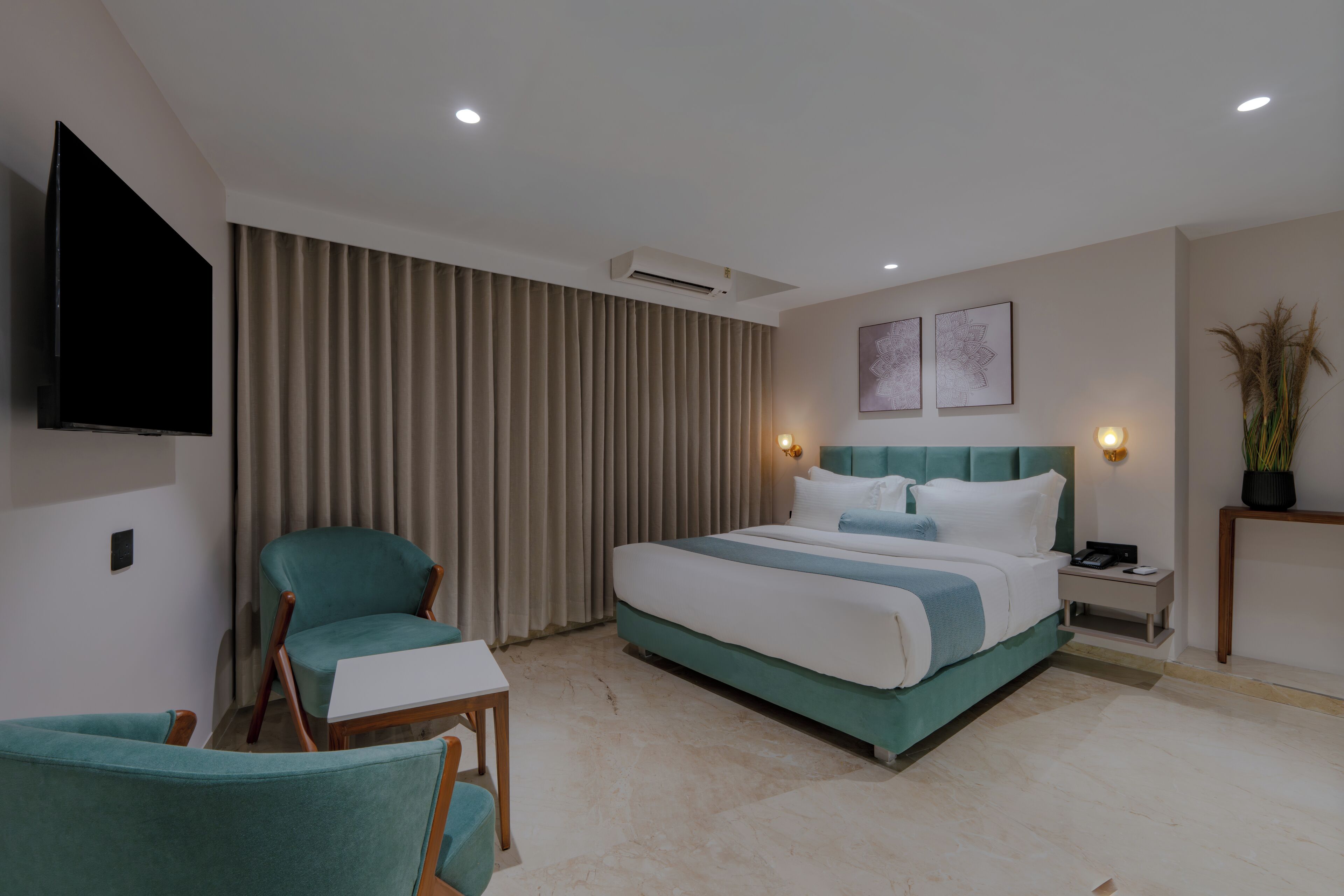 A modern hotel room with a large bed, a television, a desk, and a chair.