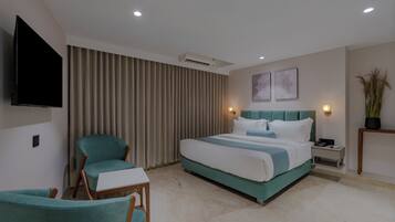 A modern hotel room with a large bed, a television, a desk, and a chair.
