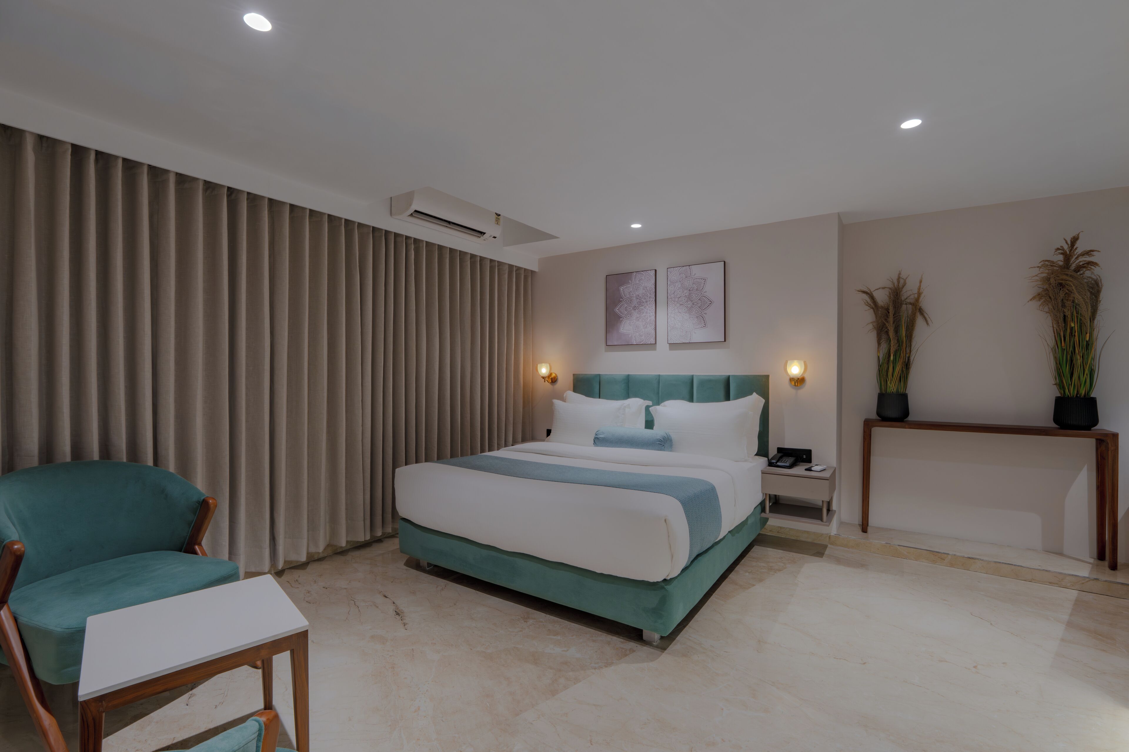 A modern hotel room with a bed, a chair, a bedside table, and two wall-mounted lamps.