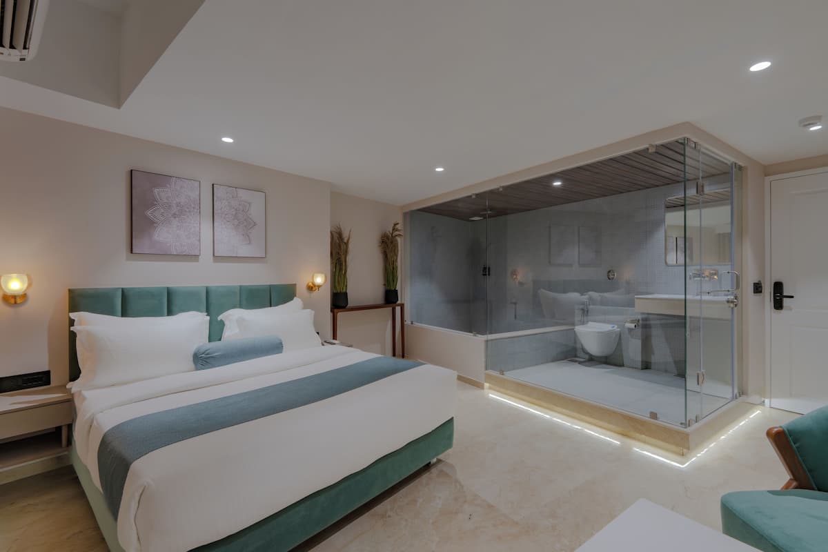 Une chambre moderne avec un grand lit, une douche en verre et un petit coin salon.