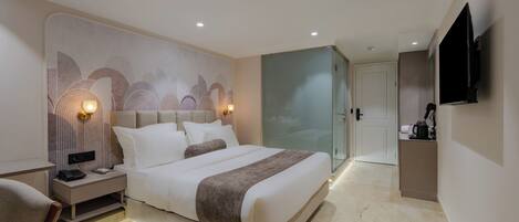 A modern hotel room with a large bed, bedside tables, a flat-screen TV, and a glass door leading to a bathroom.