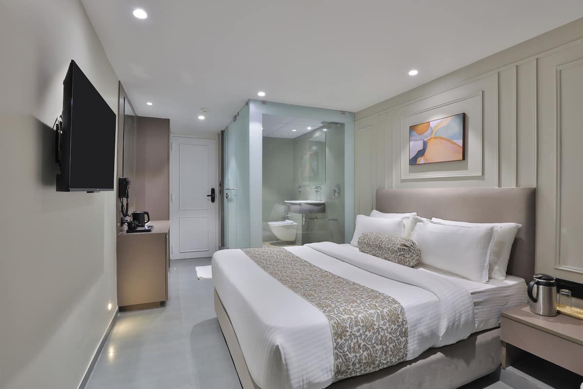 Une chambre d’hôtel moderne avec un grand lit, une table de chevet et un téléviseur fixé au mur.
