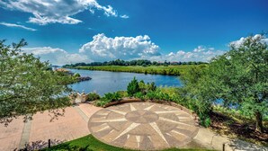 A circular paved area with a compass design, a river, and a park with trees and a bridge.