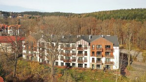 A multi-story hotel with balconies, surrounded by autumn foliage and a forested hillside. - RentPlanet - Holiday Mountain Residence (Swieradow-Zdroj)