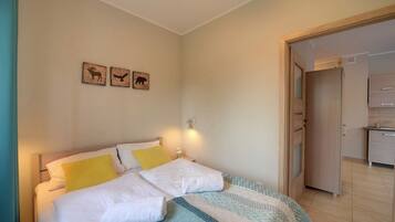A bedroom with a bed, bedside lamps, and a door leading to a bathroom.