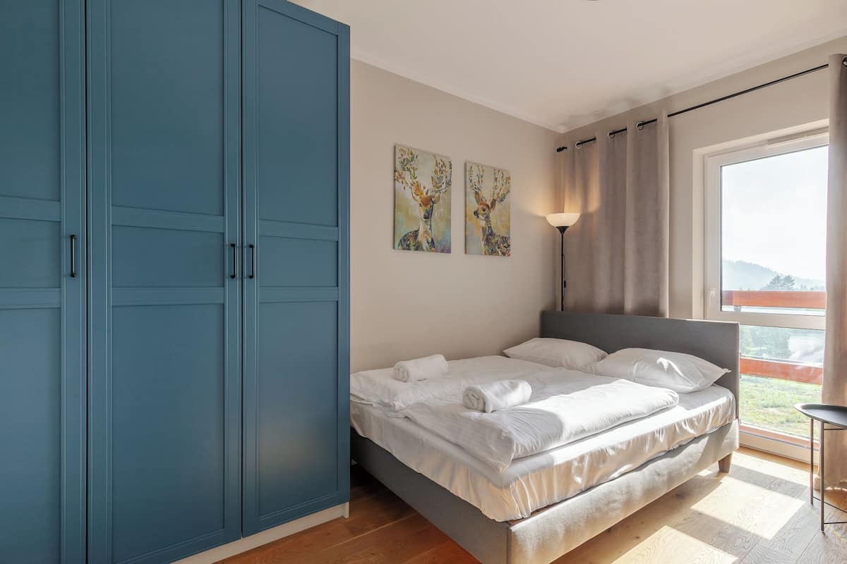 A bedroom with a bed, a wardrobe, and two wall-mounted paintings.