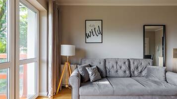 A modern living room with a grey sofa, a floor lamp, and a framed quote on the wall.