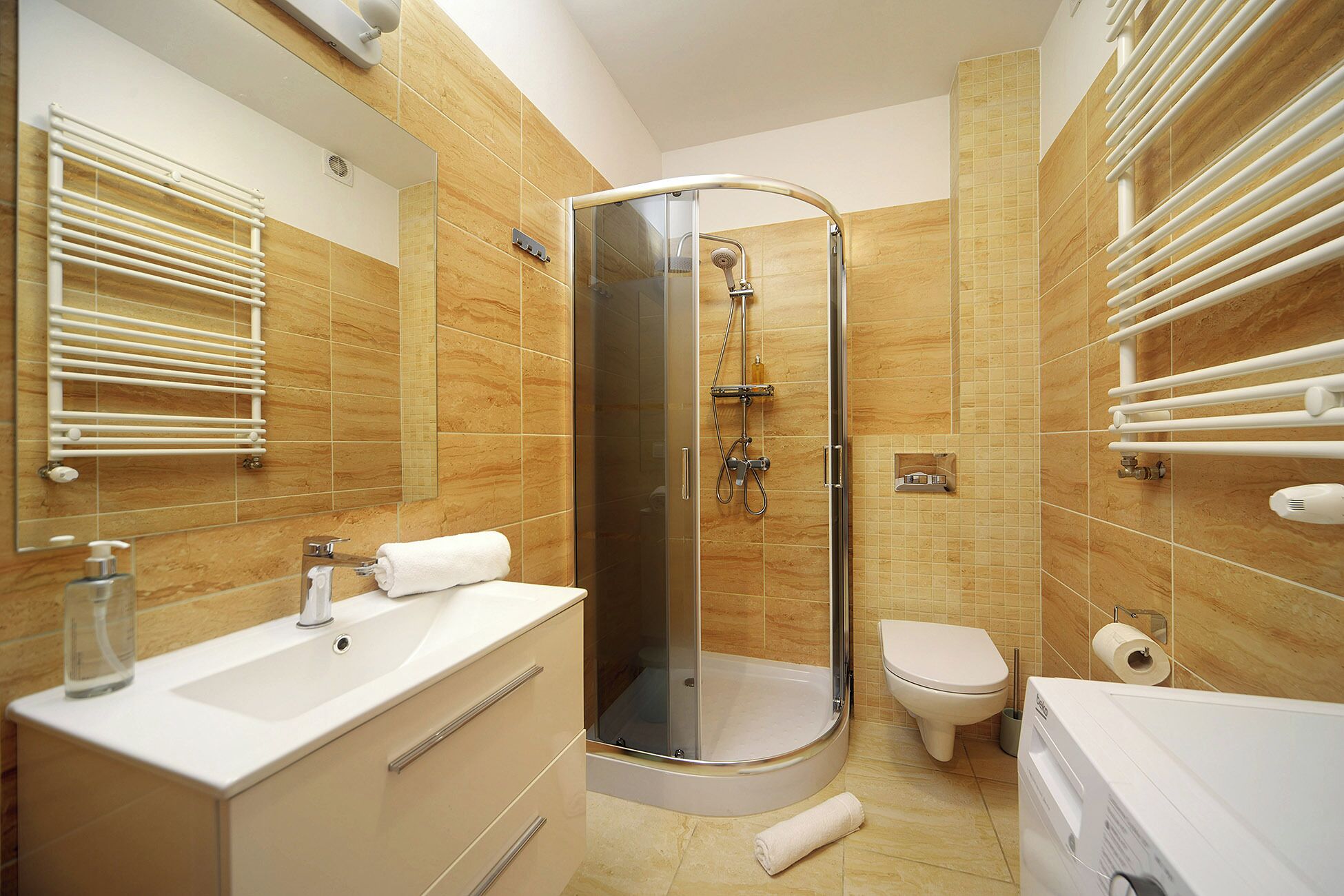 A modern bathroom with a glass-enclosed shower, a toilet, a sink with a mirror, and towel racks.