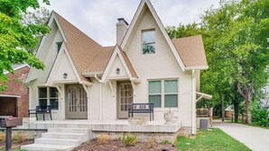 A two-story house with a steeply pitched roof, a front porch with steps, and a small garden area. - Walk to Five Points: East Nashville Home w/ Yard! (Nashville)