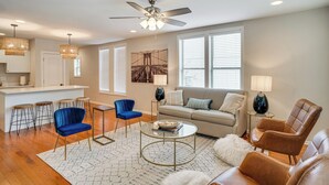 A modern living room with a sofa, two armchairs, a coffee table, and a dining area with stools. - Walk to Five Points: East Nashville Home w/ Yard! (Nashville)