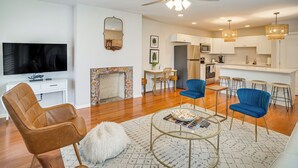 A modern living room with a TV, leather chair, and a fireplace. - Walk to Five Points: East Nashville Home w/ Yard! (Nashville)