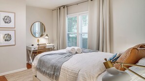 A neatly arranged bedroom with a bed, bedside table, lamp, and two framed pictures on the wall. - Walk to Five Points: East Nashville Home w/ Yard! (Nashville)