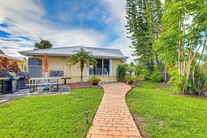 Una casa con entrada pavimentada, un patio con mobiliario exterior y un césped bien cuidado.