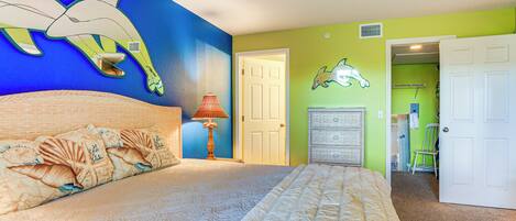 Une chambre à coucher avec un lit, une peinture murale, une lampe et une porte donnant sur une autre pièce.