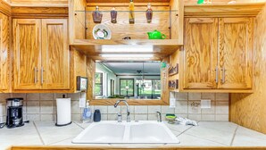 A kitchen with wooden cabinets, a double sink, and a Bosch dishwasher. - Pensacola Home ~ 13 Mi to Perdido Bay! (Pensacola)