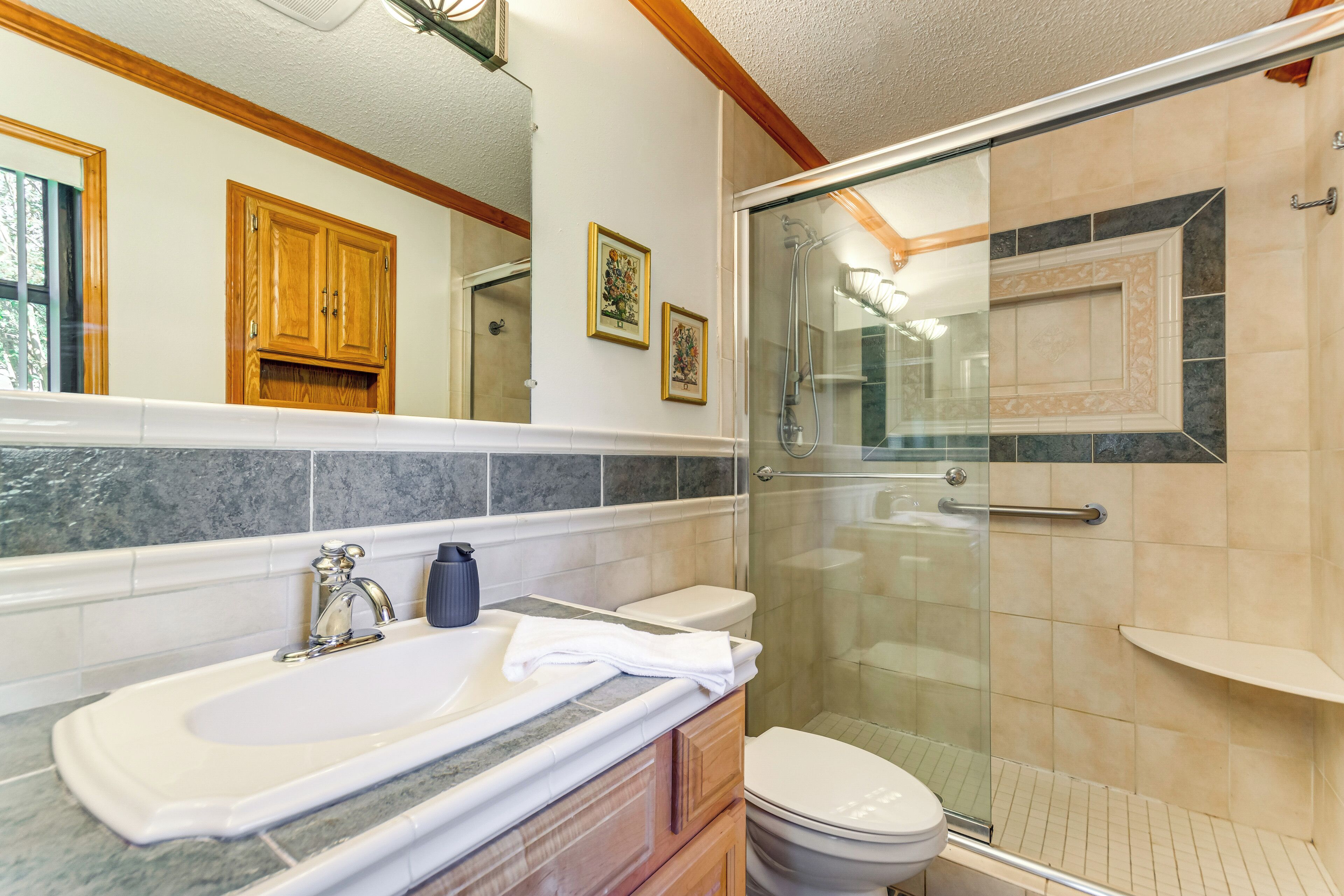 A bathroom with a glass-enclosed shower, a white sink, and a toilet.