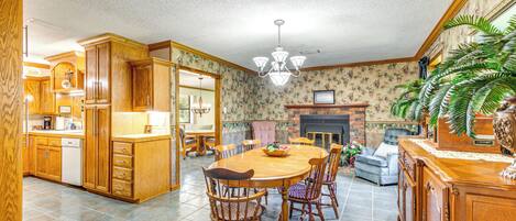A spacious kitchen with wooden cabinets, a dining table with chairs, and a fireplace.