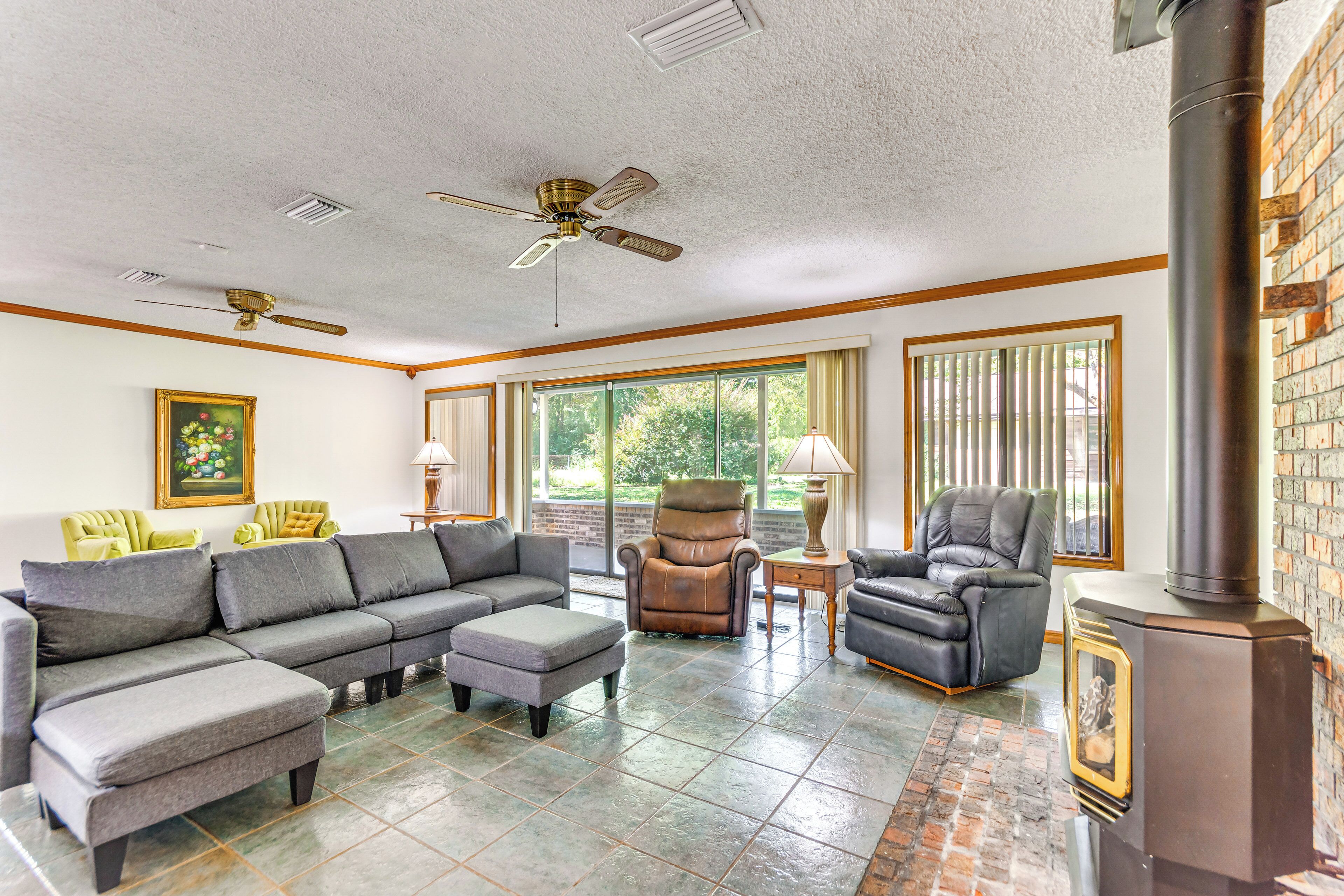 A living room with a sectional sofa, two armchairs, a fireplace, and large windows.
