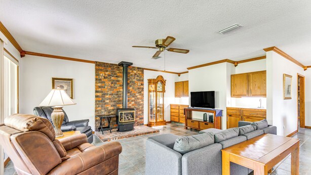 A living room with leather recliners, a grey sofa, a wooden coffee table, a brick fireplace, and a ceiling fan. - Pensacola Home ~ 13 Mi to Perdido Bay! (Pensacola)