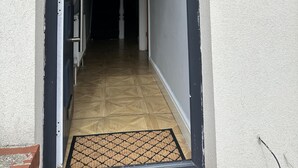 Un couloir menant à une porte surmontée d’un paillasson.