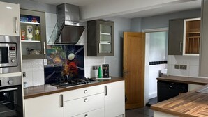 Une cuisine moderne avec des armoires blanches, un four encastré, un four à micro-ondes, une cuisinière à gaz et un lave-vaisselle.