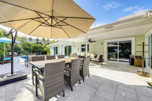 An outdoor patio with a dining table, chairs, and a large umbrella. - 2 Mi to Deerfield Beach: Home w/ Outdoor Oasis! (Deerfield Beach)