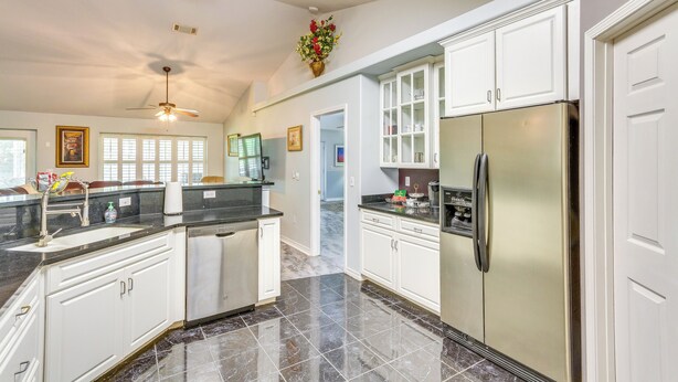 A modern kitchen with white cabinets, a stainless steel refrigerator, and a black countertop. - 4 Mi to Beach: Family-friendly Home in Navarre (Navarre)