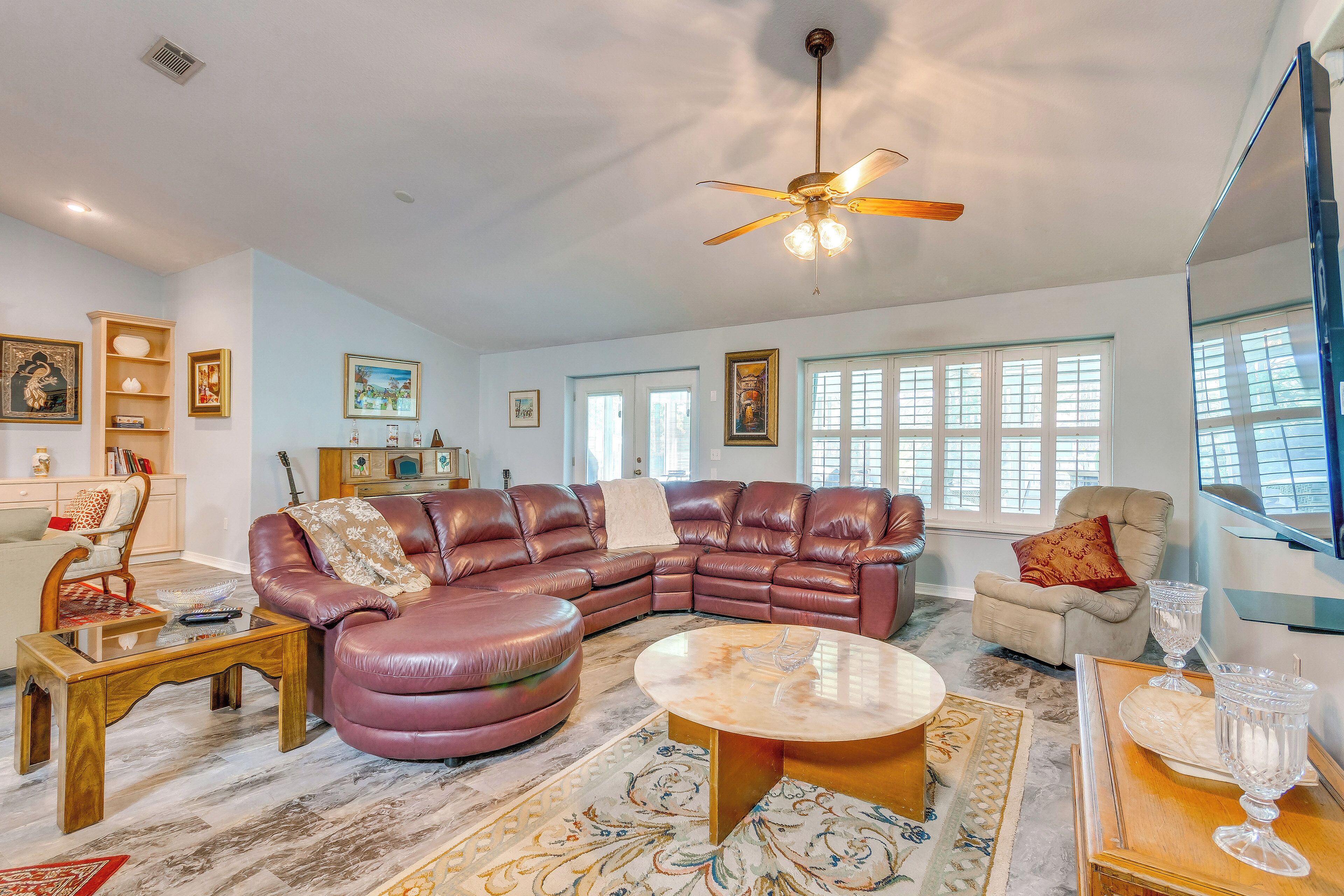 Ett rymligt vardagsrum med en hörnsoffa, ett soffbord och en takfläkt.